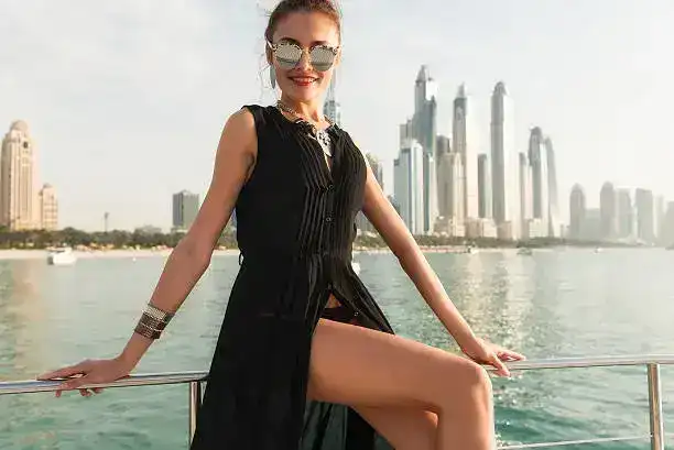 Woman in black dress posing on yacht in Dubai.
