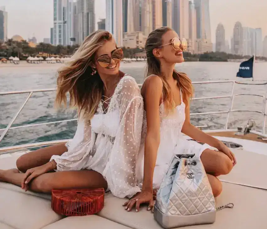 Two women in white outfits posing on a yacht.