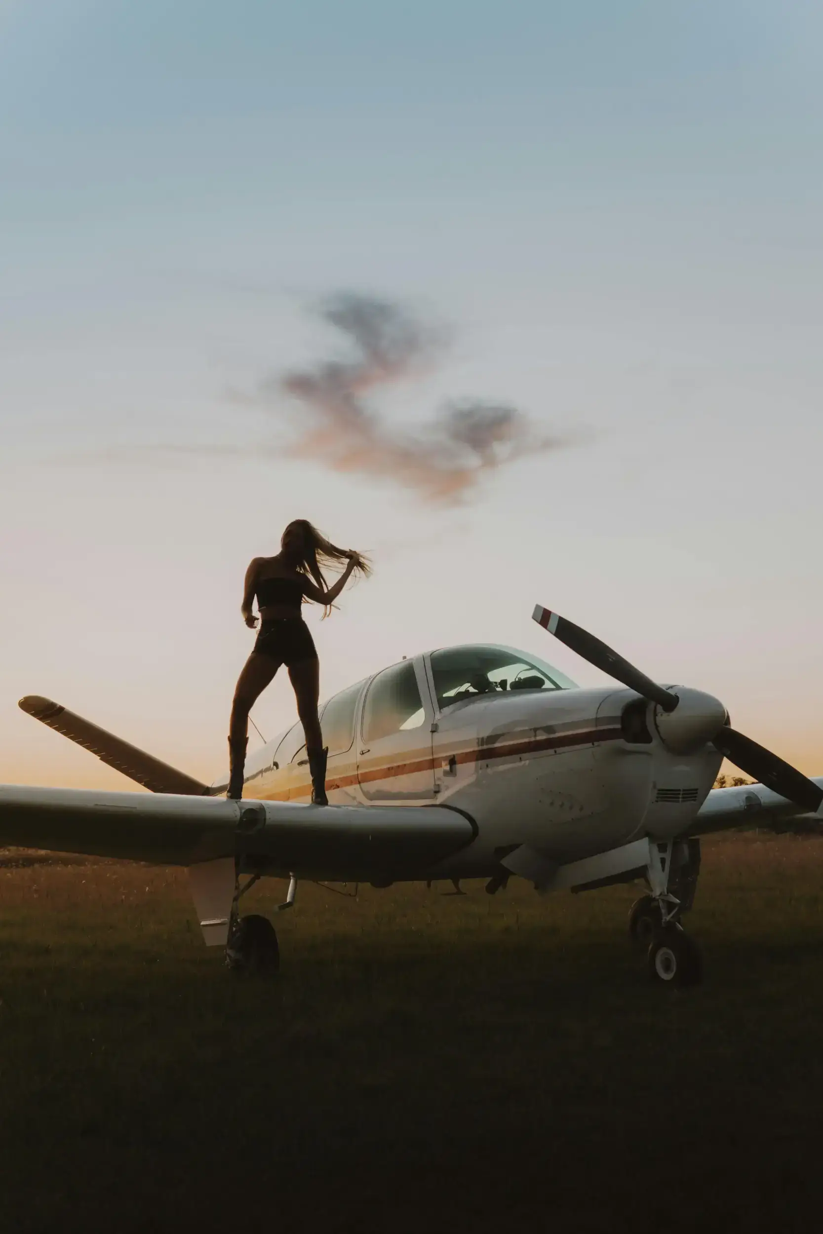 Silhouette of a woman standing on a light aircraft wing.