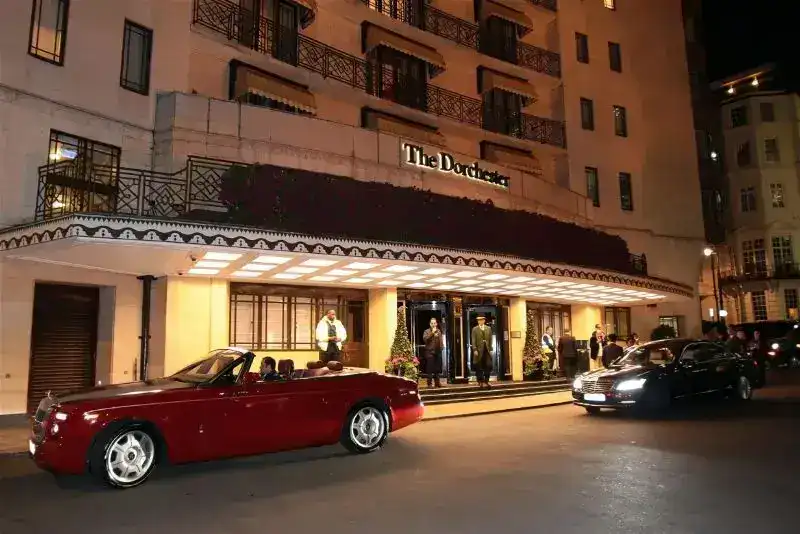 Red Rolls-Royce parked outside The Dorchester hotel at night.