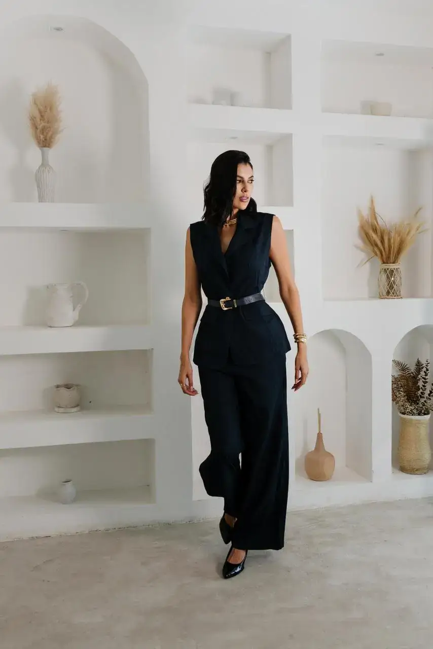 Woman in a black sleeveless blazer and wide-leg trousers.