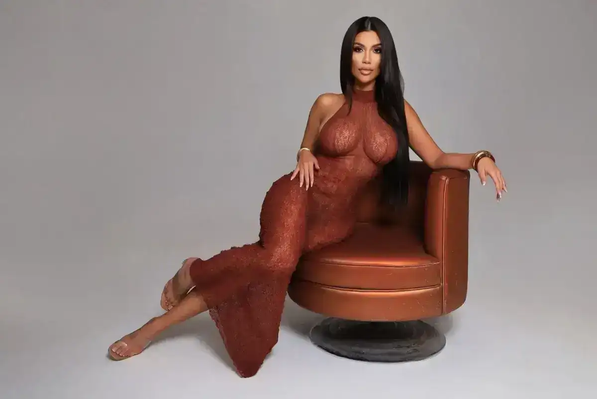 Woman in a brown lace dress sitting in an armchair.