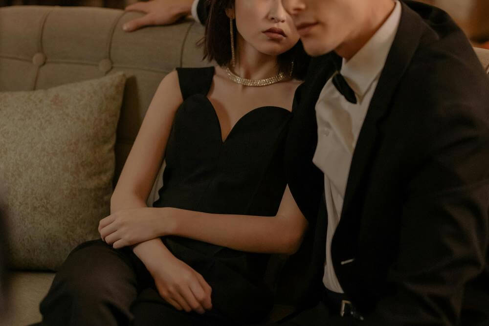 A couple in elegant evening wear on a sofa.