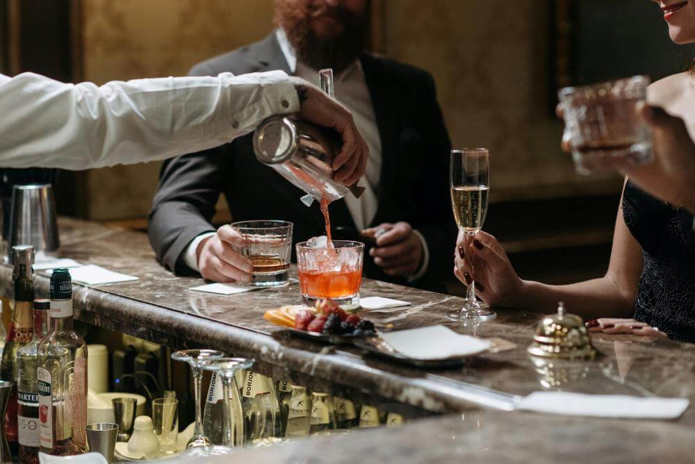Bartender pouring a cocktail for guests at an upscale bar.
