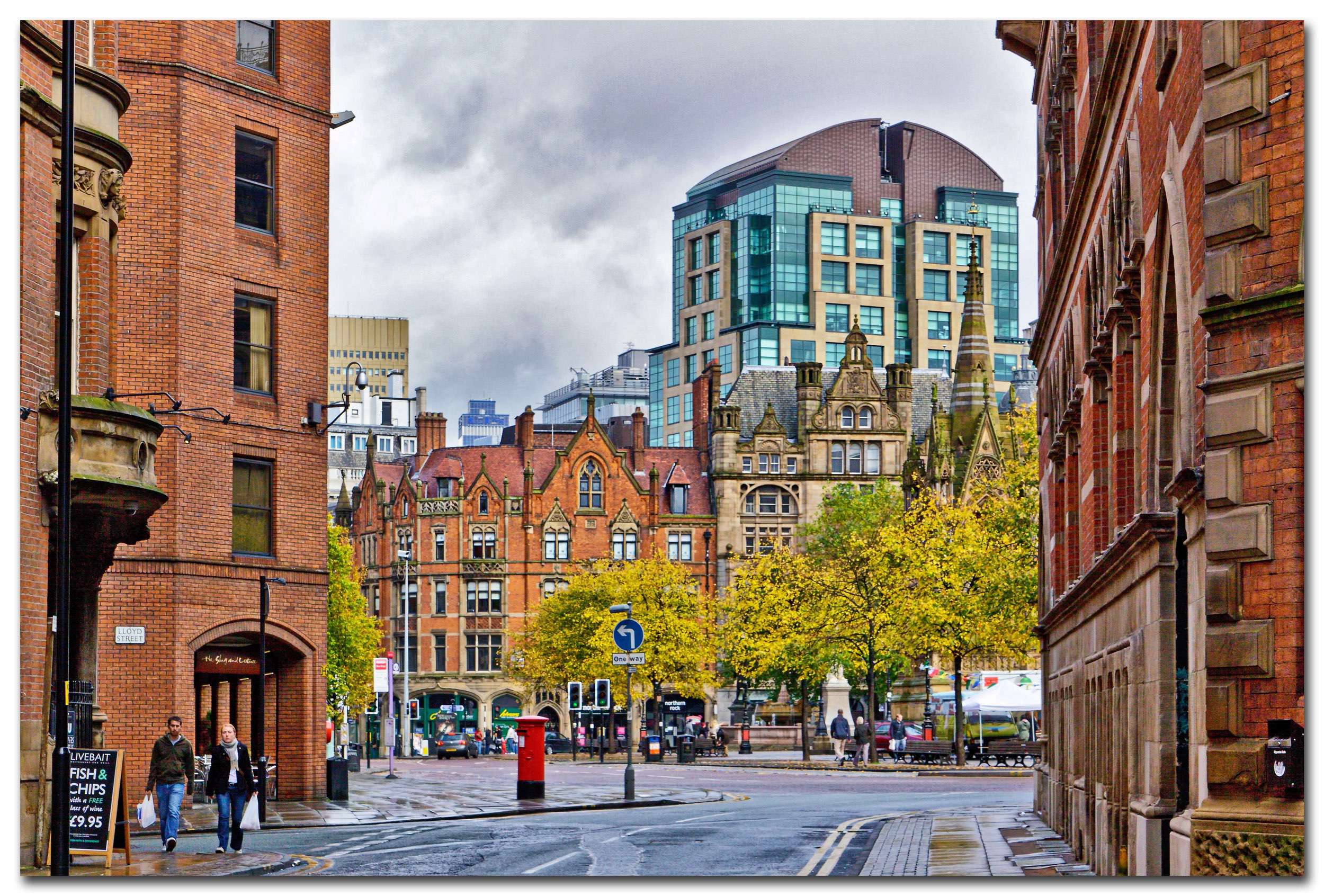 Autumnal street scene in Manchester with red brick buildings.